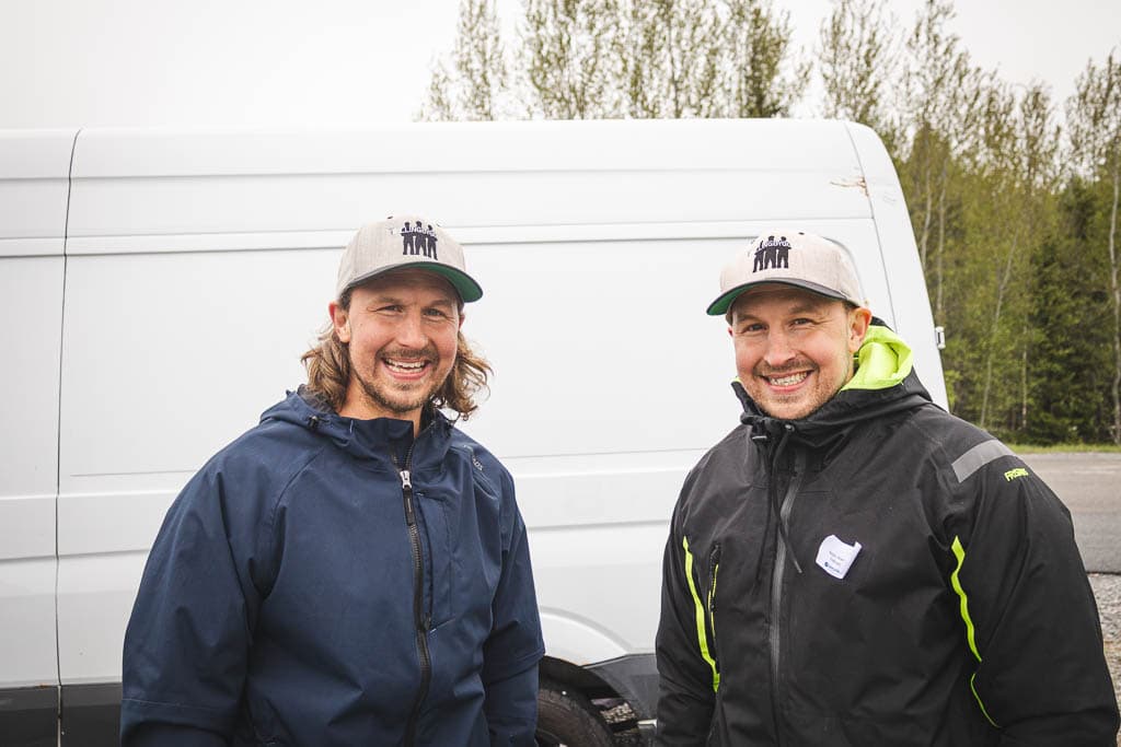 two men standing in front of a van