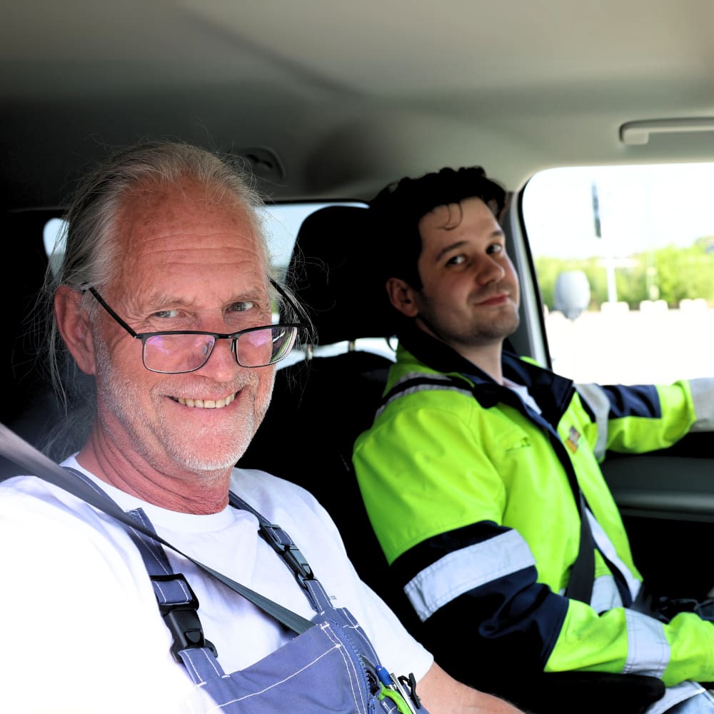 a man in a car with a man in a safety vest
