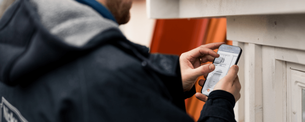 Person använder mobil för byggplaner